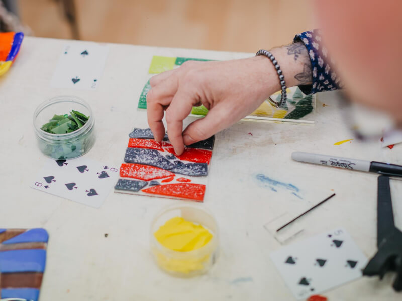 Close up of hands creating a colourful mosaic